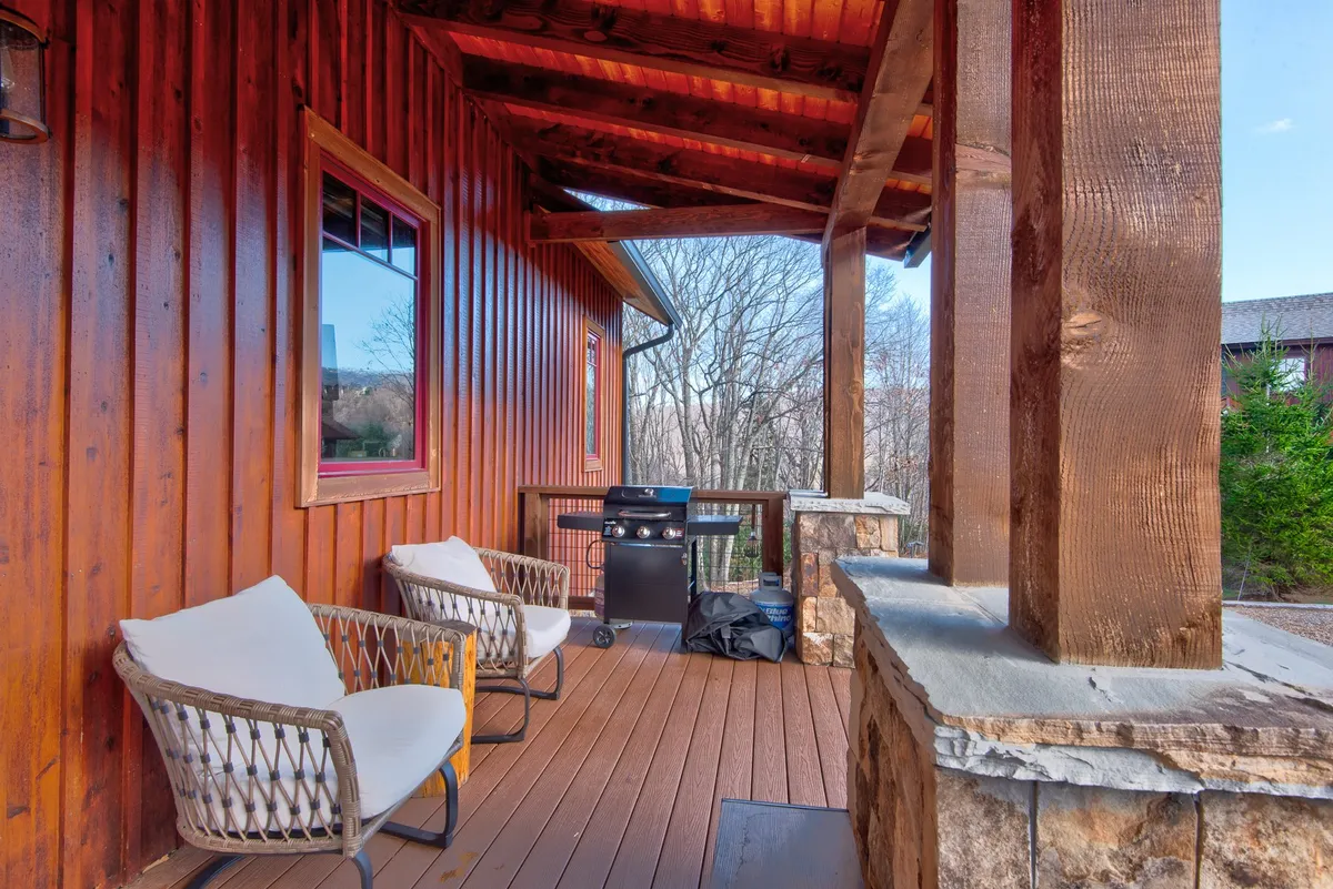 The image captures an outdoor area with a wooden structure for shade, comfortable seating, a grill, and a stone wall. This space encourages outdoor dining, social gatherings, and appreciation of nature in a setting that's easy to navigate and use for all ages.