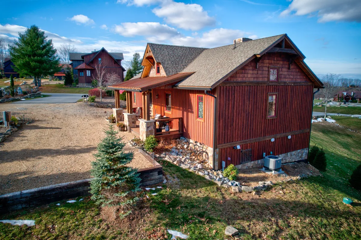 This exterior view showcases the wooden facade and landscaped garden of the home, with a stone pathway leading to a welcoming front porch. The setting feels inviting and accessible, suggesting easy transitions from indoor comfort to outdoor adventures.