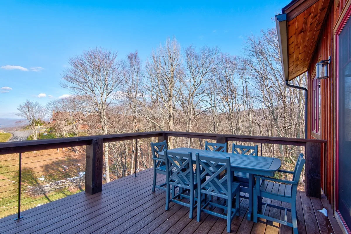 A tranquil exterior scene with a dining table set among surrounding trees and a backdrop of rolling mountain views. The natural setting invites outdoor dining or relaxing with a glass of wine amid the fresh mountain air.
